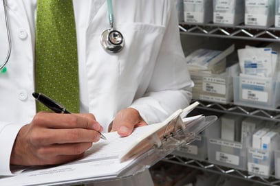 Doctor writing on clipboard in hospital supply room