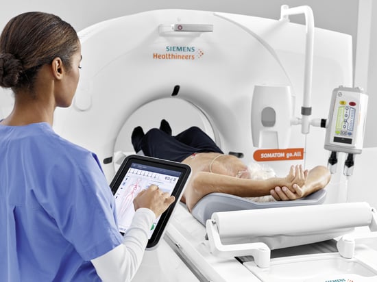 Provider using a tablet to communicate and work during a CT scan